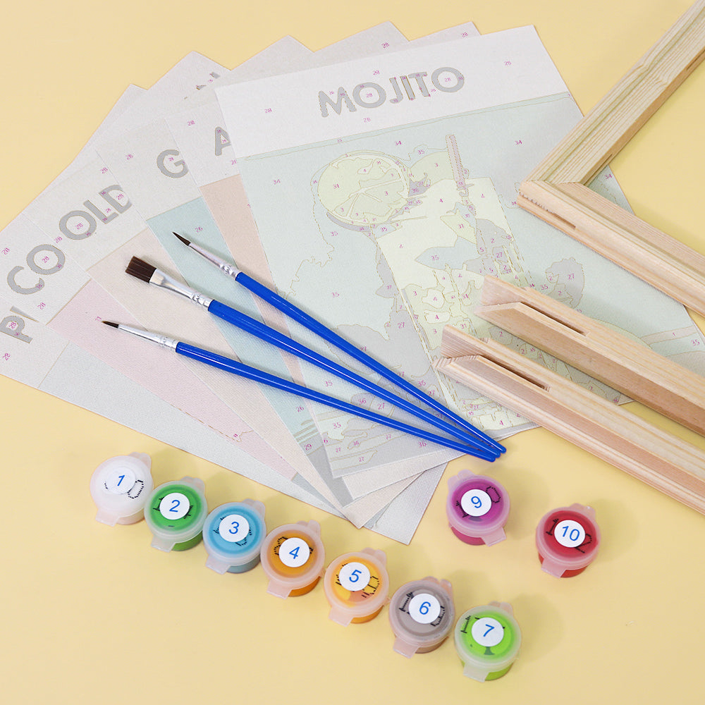 Sip Society paint by numbers kit by Artspark, including unpainted linen canvases featuring cocktail designs, wooden frame parts, paint pots, and brushes. Preparation phase before painting.