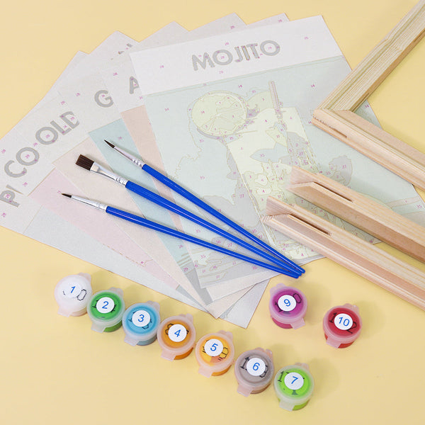 Sip Society paint by numbers kit by Artspark, including unpainted linen canvases featuring cocktail designs, wooden frame parts, paint pots, and brushes. Preparation phase before painting.