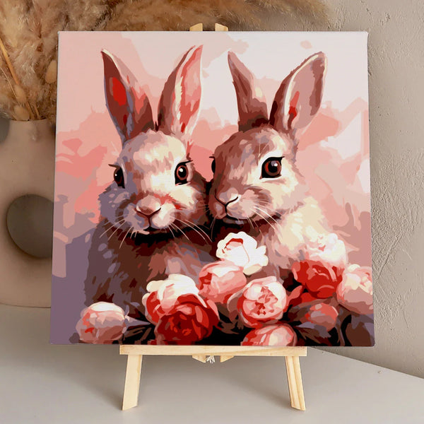 Two adorable rabbits surrounded by pink and red blooming flowers