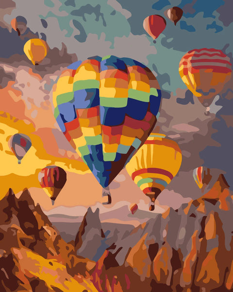 Colorful hot air balloons floating over a mountainous landscape at sunset