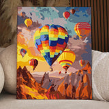Colorful hot air balloons floating over a mountainous landscape at sunset