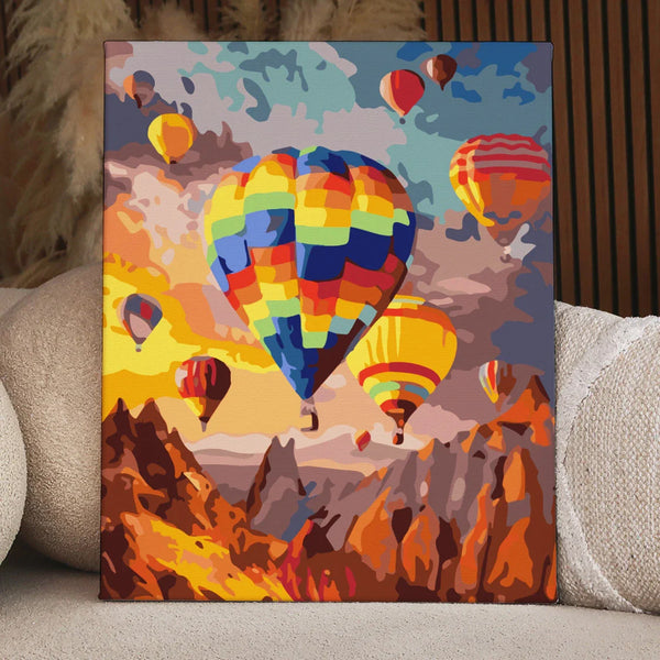 Colorful hot air balloons floating over a mountainous landscape at sunset