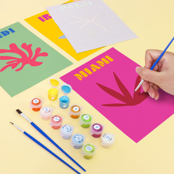 Coastal Dreams Paint by Numbers Kit by Artspark showing the painting process of the Miami canvas with paint pots, brushes, and colorful designs.