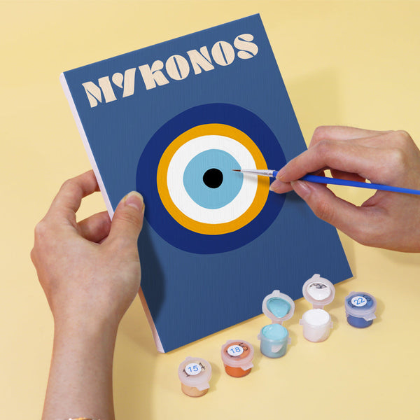 Coastal Dreams Paint by Numbers Kit by Artspark showing the painting process of the Mykonos canvas featuring a Greek evil eye design, with paint pots and brush.