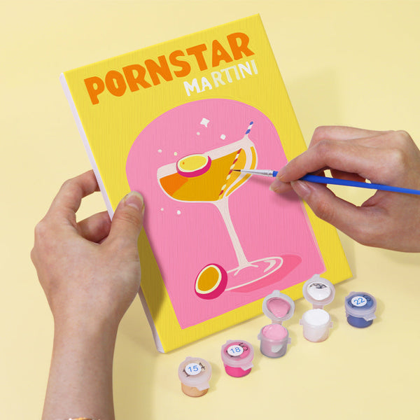 Painting a Pornstar Martini cocktail canvas from the Cocktail Cuties Paint by Numbers Kit by Artspark - Featuring bright colors, brushes, and numbered paints.
