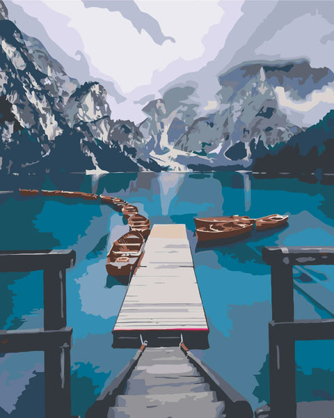 Scenic mountain lake with wooden dock and boats in calm water