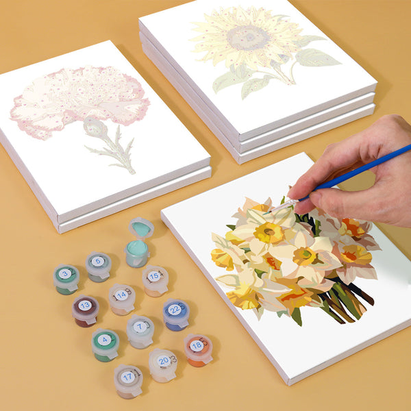 Painting process of a daffodil bouquet from the Garden Whispers Paint by Numbers Kit. Shows partially painted canvas, acrylic paint pots, and brushes from the Artspark kit.