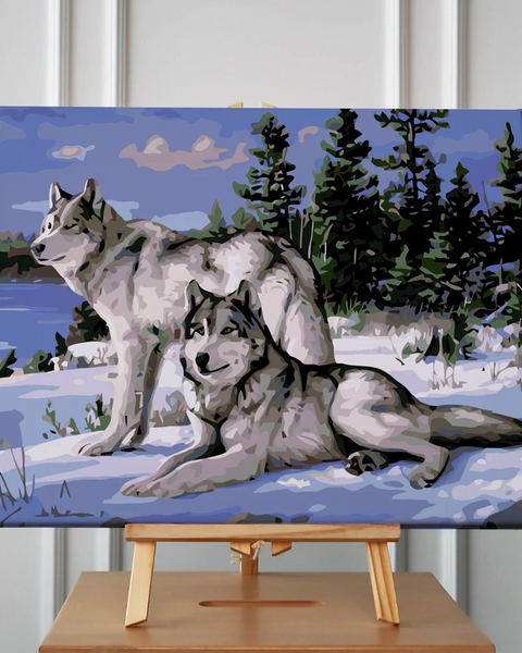 Two wolves in a snowy forest with a lake background