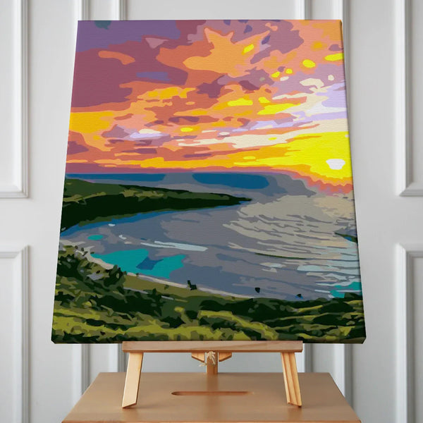 Vibrant sunset over an ocean bay with lush green hills