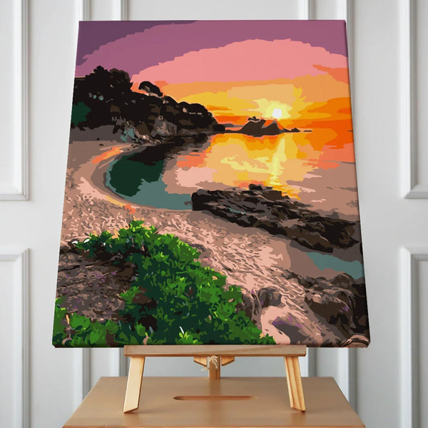 Beach sunset painting with rocky shore, calm water, and vibrant sky