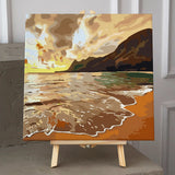 Golden beach sunset painting with waves, mountains, and dramatic sky