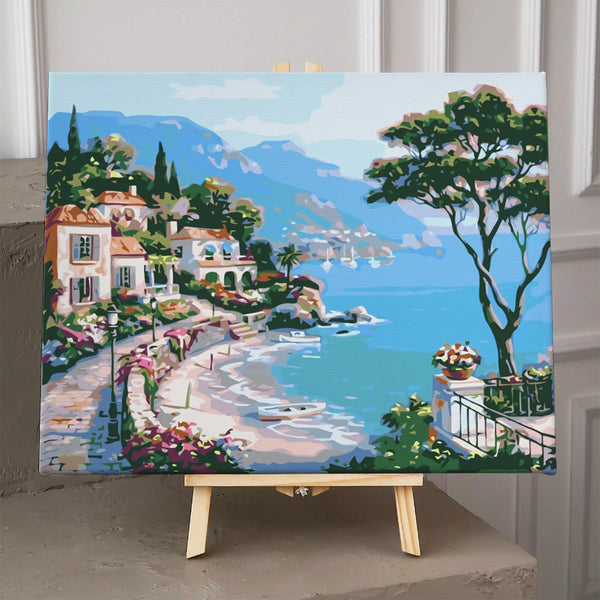 Coastal village painting with seaside villas, blue water, and boats