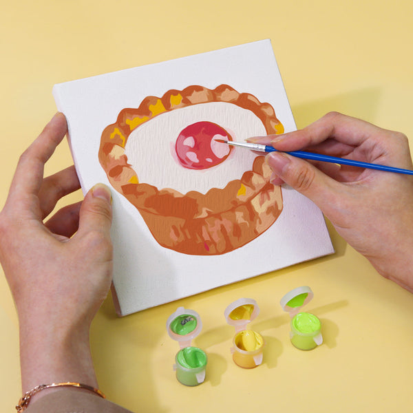 Sugar & Whimsy Paint by Numbers Kit by Artspark showing the painting process of a raspberry tart canvas with paint pots and brush.