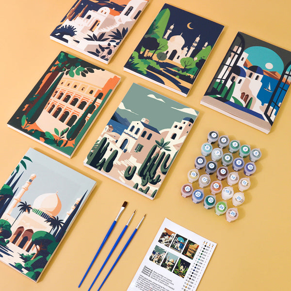 Completed paintings from the Wanderlust Wonders set with brushes and paint pots, ready for final touches.