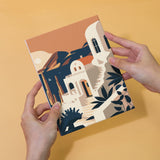 Hand holding completed painting from the Wanderlust Wonders set, featuring a Mediterranean-inspired architectural design.
